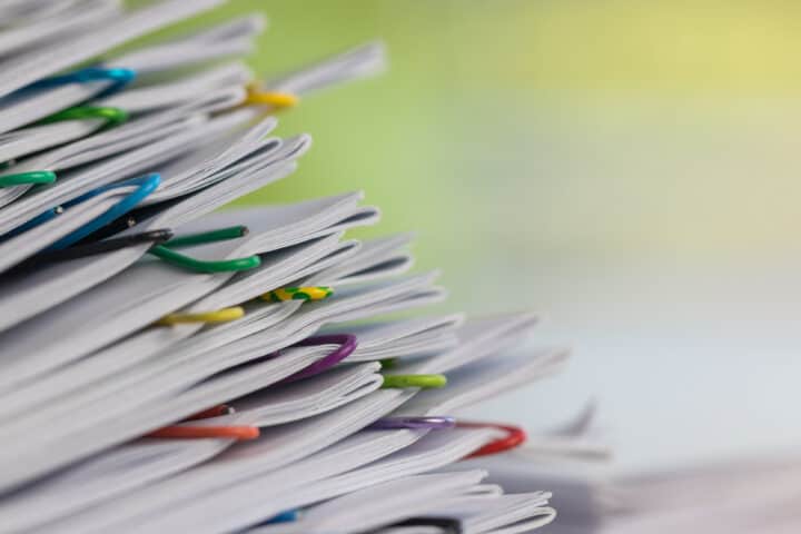 Close up pile of unfinished paperwork on office desk