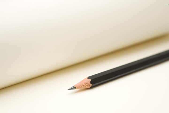 Pencil lying on a blank notepad. Selective focus on tip of the pencil.