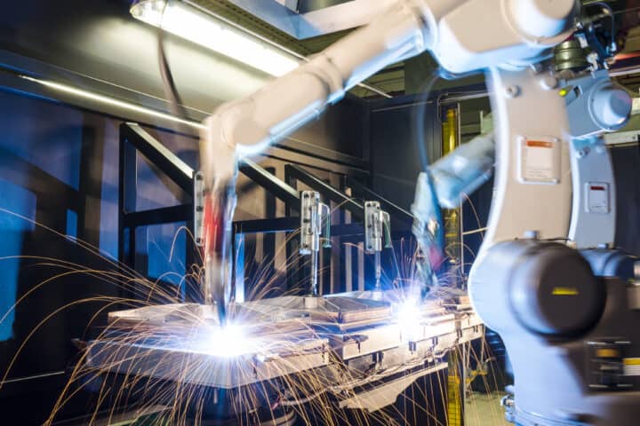 High-tech, industrial robotic welding machines in operation in a metal manufacturing plant.