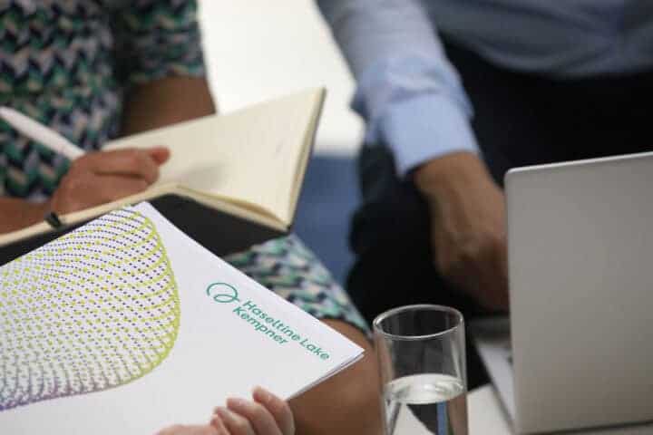 HLK colleagues sat around a laptop, one of them holding a HLK-branded folder